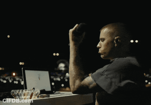 A Man Sits At A Table Using A Laptop And Drinking A Cup Of Coffee GIF