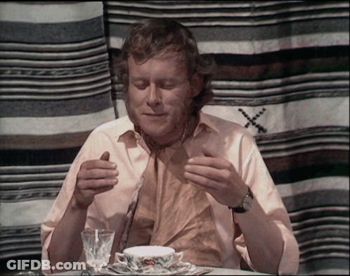 A Man Sits At A Table With A Cup Of Tea GIF
