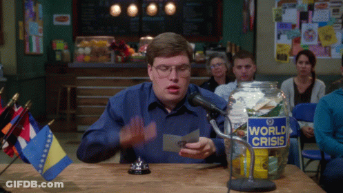 A Man Sits At A Table With A Jar That Says World Crisis On It GIF