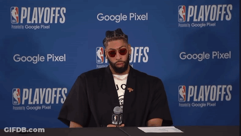 A Man Sits At A Table With A Microphone In Front Of A Google Pixel Banner GIF