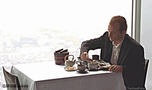 A Man Sits At A Table With A White Table Cloth And The Good Films Logo GIF