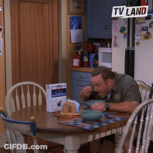 A Man Sits At A Table With Bowls Of Food Under A Tv Land Banner GIF