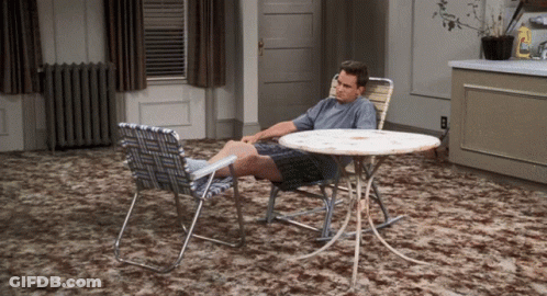 A Man Sits At A Table With His Feet On The Table GIF