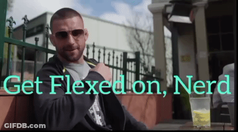 A Man Sits At A Table With The Words Get Flexed On Nerd GIF