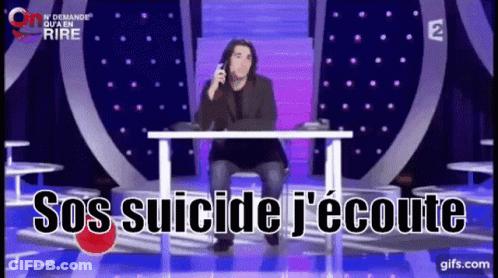 A Man Sits At A Table With The Words Sos Suicide J'écoute Written On The Screen GIF
