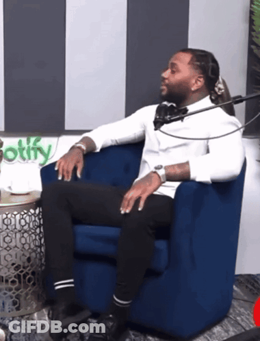A Man Sits In A Blue Chair In Front Of A Spotify Logo GIF
