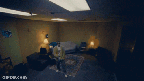 A Man Sits In A Chair In A Living Room With A Couch And Rug GIF