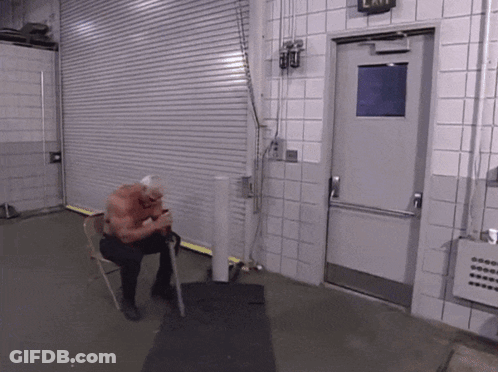 A Man Sits In A Chair In Front Of A Door That Has An Exit Sign On It GIF