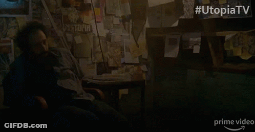 A Man Sits In A Chair In Front Of A Wall With Papers On It And The Words Utopia Tv On The Bottom GIF