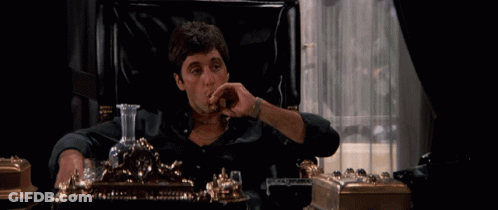 A Man Sits In A Chair Smoking A Cigar And Drinking From A Decanter GIF