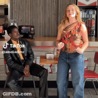 A Man Sits In A Chair While A Woman Stands In Front Of Him With A Tiktok Watermark GIF