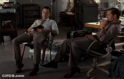 A Man Sits In A Chair With His Feet Up While Another Man Sits In A Chair GIF