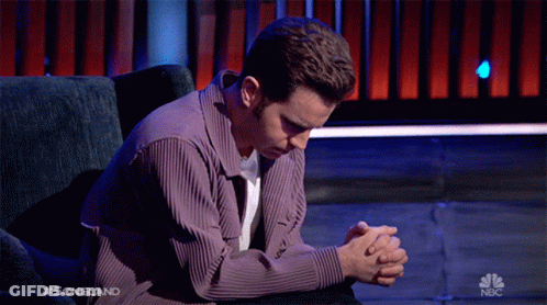 A Man Sits In A Chair With His Hands Folded In Prayer On A Nbc Show GIF