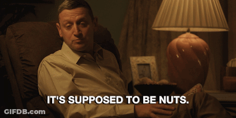 A Man Sits In A Chair With The Words It 'S Supposed To Be Nuts GIF