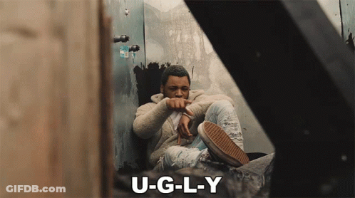 A Man Sits In A Corner With The Words U-G-L-Y Below Him GIF
