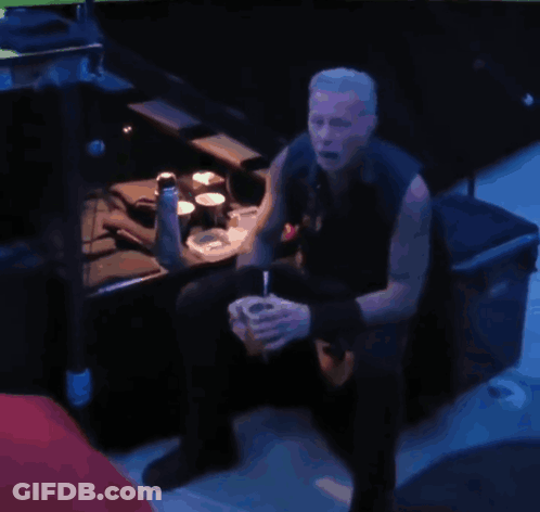 A Man Sits In A Dark Room Drinking From A Cup GIF