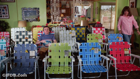 A Man Sits In A Row Of Lawn Chairs With A Yellow Tag That Says ' Lawn Chairs ' GIF