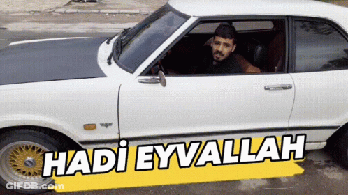 A Man Sits In A White Car With The Words Hadi Eyvallah On The Side GIF