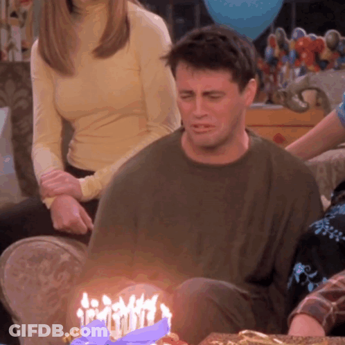 A Man Sits In Front Of A Birthday Cake With Candles GIF