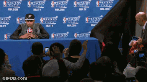 A Man Sits In Front Of A Wall That Says Western Conference Finals On It GIF