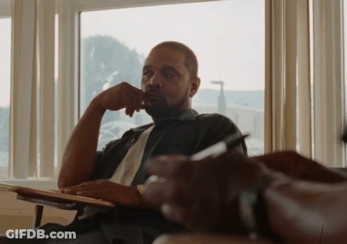 A Man Sits In Front Of A Window With His Hand To His Chin GIF