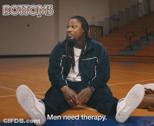 A Man Sits On A Basketball Court With The Words Men Need Therapy Above Him GIF