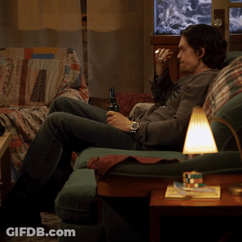 A Man Sits On A Couch Drinking A Beer GIF