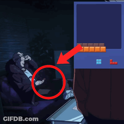 A Man Sits On A Couch Looking At His Phone Next To A Tetris Screen GIF