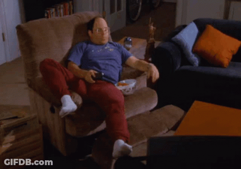 A Man Sits On A Couch With A Shelf Full Of Cans And Snacks GIF