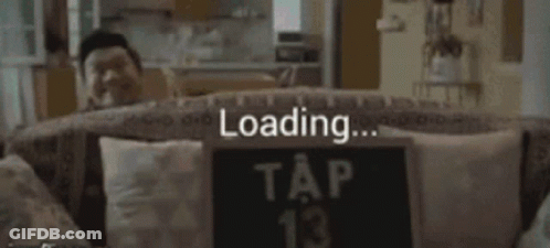 A Man Sits On A Couch With A Sign That Says Tap 13 GIF