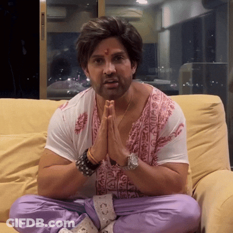 A Man Sits On A Couch With His Hands Folded In Front Of His Face GIF