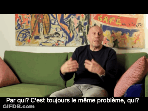A Man Sits On A Green Couch In Front Of A Cafe Painting GIF