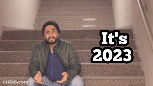 A Man Sits On A Set Of Stairs With The Words " It 'S 2023 " On The Bottom GIF
