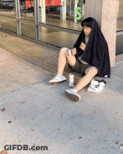 A Man Sits On The Sidewalk In Front Of A Store That Says Mark 'S GIF