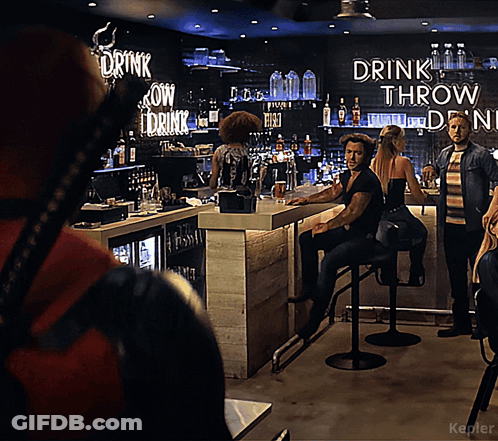 A Man Sitting At A Bar With A Sign That Says Drink Throw Drink GIF