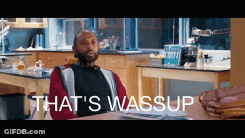 A Man Sitting At A Desk In A Kitchen With The Words That 'S Wassup On The Bottom GIF