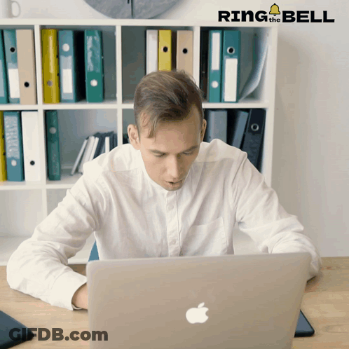 A Man Sitting At A Desk Looking At A Laptop With Ring The Bell Written On The Bottom GIF