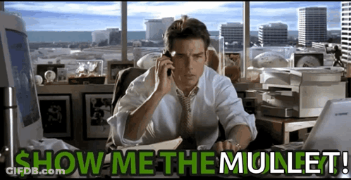 A Man Sitting At A Desk Talking On A Cell Phone With The Words Show Me The Mullet Written Below Him GIF