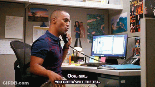 A Man Sitting At A Desk Talking On A Phone With The Words Ooh Girl You Gotta Spill The Tea GIF