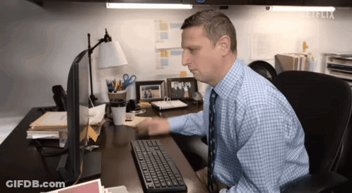 A Man Sitting At A Desk Using A Computer With Netflix Written On The Corner GIF