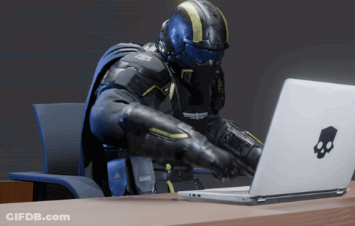A Man Sitting At A Desk Using A Laptop With A Skull And Crossbones Logo GIF