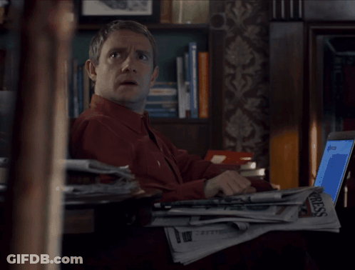 A Man Sitting At A Desk With A Stack Of Newspapers And A Laptop With The Word Press On It GIF
