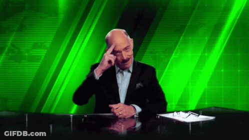 A Man Sitting At A Desk With His Hand On His Forehead GIF