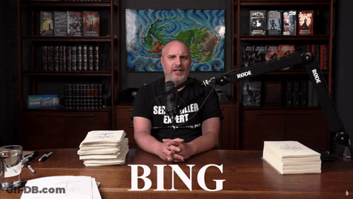 A Man Sitting At A Desk With The Word Bing On The Top GIF