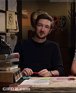 A Man Sitting At A Desk With The Words Delusionalforharmony Written On The Bottom GIF