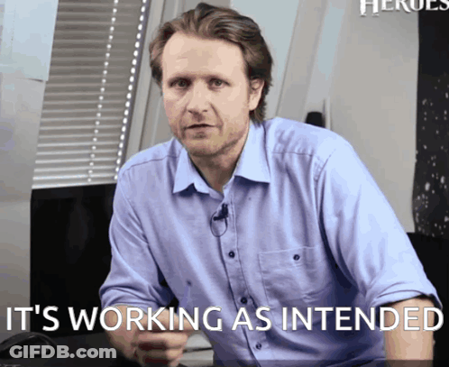 A Man Sitting At A Desk With The Words " It 'S Working As Intended " Behind Him GIF