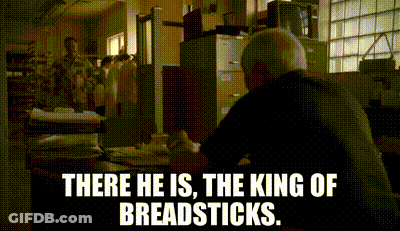 A Man Sitting At A Desk With The Words " There He Is The King Of Breadsticks " GIF