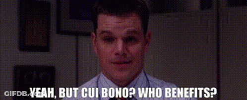 A Man Sitting At A Desk With The Words Yeah But Cui Bono Who Benefits Written Below Him GIF