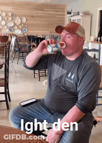 A Man Sitting At A Table Drinking From A Cup With The Words Ight Den Below Him GIF