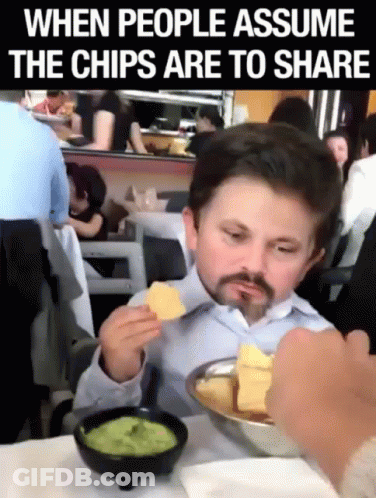 A Man Sitting At A Table Eating Chips And Guacamole GIF